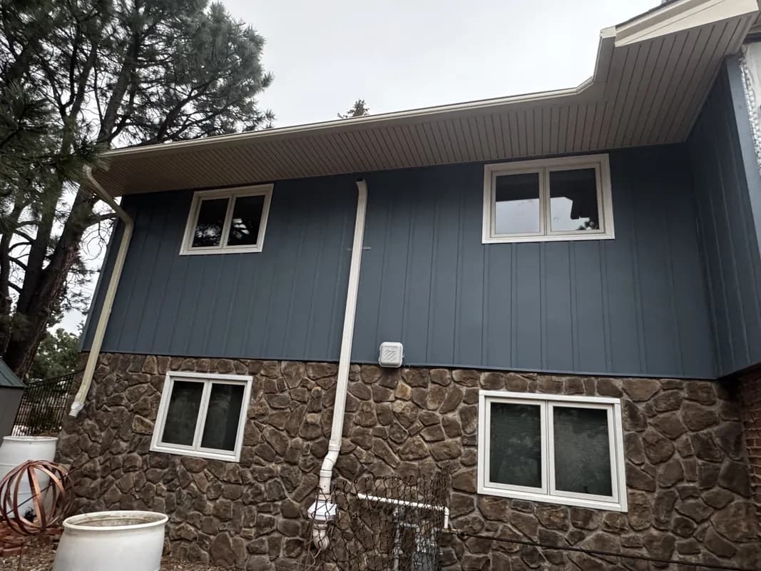 Dark blue board and batten siding with entry door and front porch