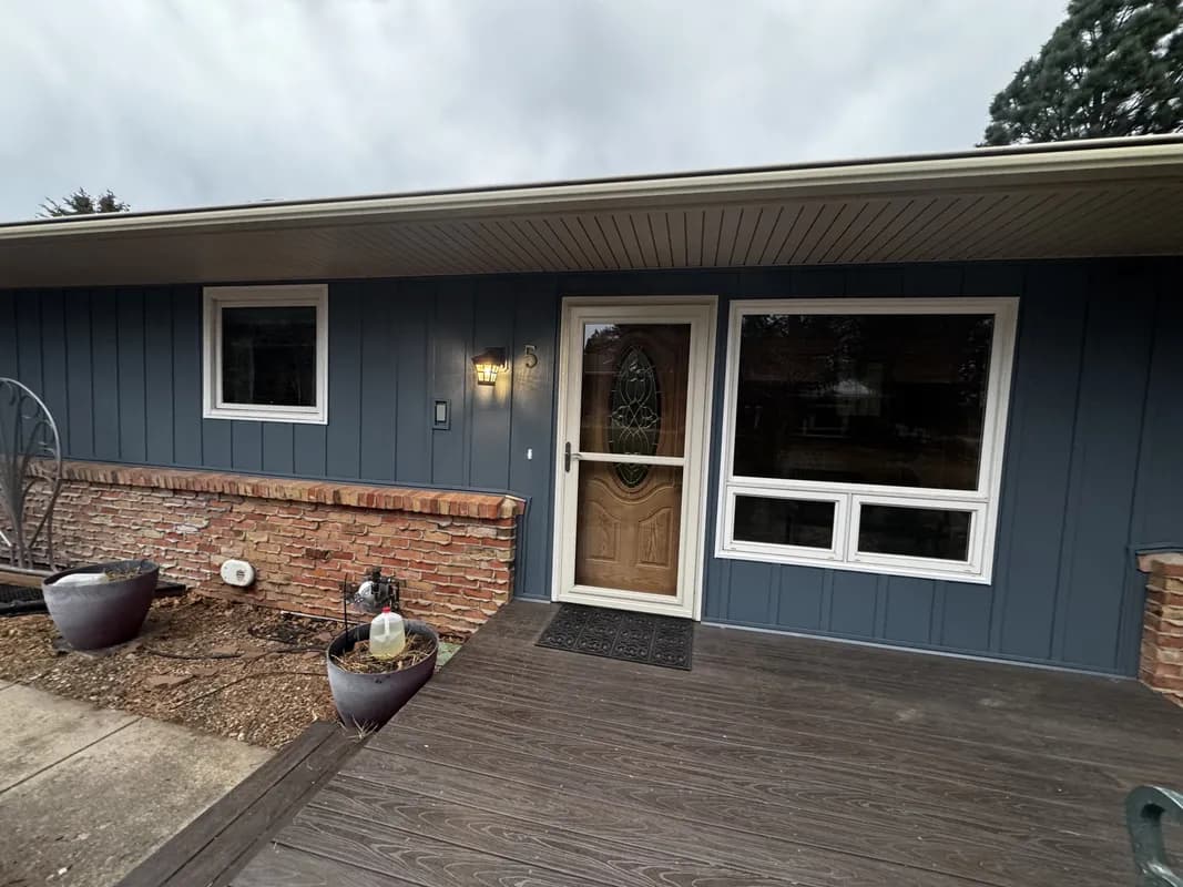 Light green composite siding installation with brick chimney